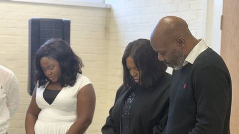 Members standing with heads bowed during a prayer meeting