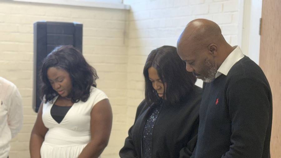 Members standing with heads bowed in prayer